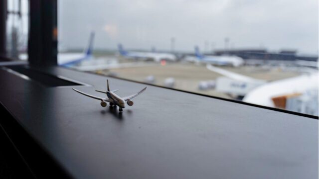 空港の窓際に置いた飛行機のミニチュアと滑走路
