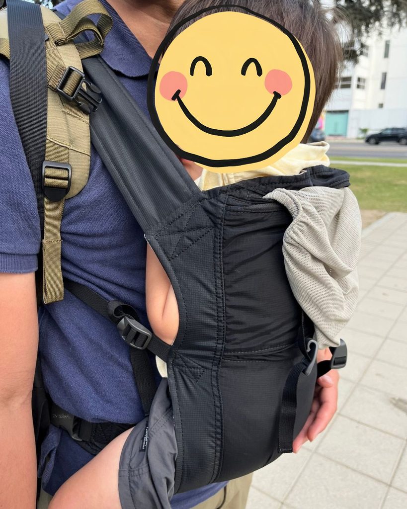 モンベルのポケッタブル抱っこ紐で子どもを抱っこして、旅行先の歩道を歩く様子
