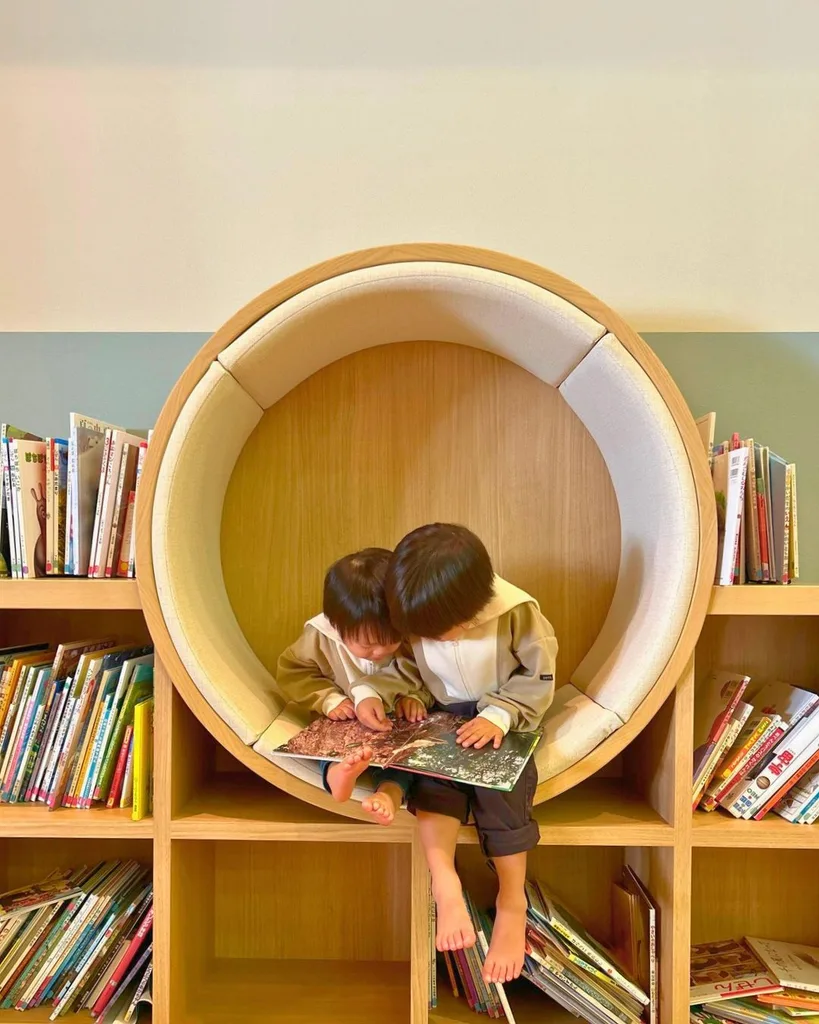 グランドメルキュール八ヶ岳のキッズスペースにある丸い本棚で、子ども2人が絵本を読む様子